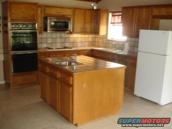 Kitchen with wood cabinets, island sink, and white refrigerator