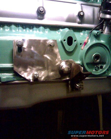 Engine block with a metal plate bolted on, showing a bracket and oil filter housing