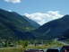 1995 Mercury Grand Marquis - A scenic mountain valley with a winding highway and scattered buildings under a blue sky with clouds.