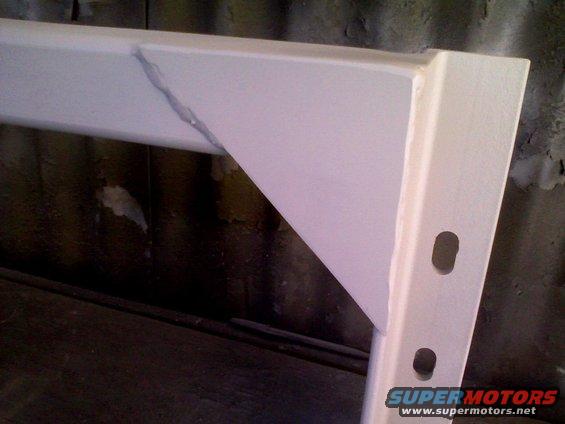 White trailer hitch with a visible crack and weld repair, showing mounting holes