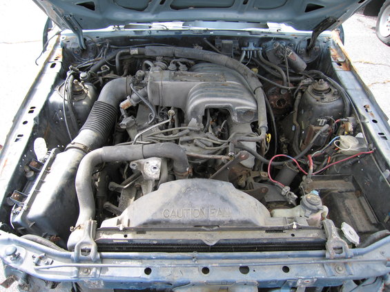 1991 Ford Crown Victoria LTD engine bay, blue exterior, dusty engine components, "CAUTION FAN" text on fan shroud