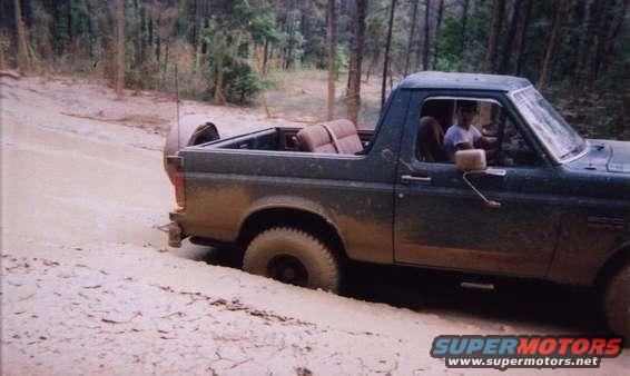 Ford Bronco stuck in mud, driver visible inside