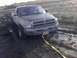 1996 Dodge 1500 - A mud-splattered Dodge Ram pickup truck is stuck in a muddy terrain, with a tow strap attached to its front.