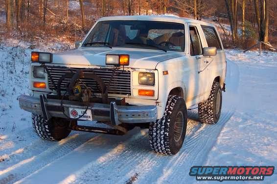 White 1980s Ford Bronco with plow attachment in snow