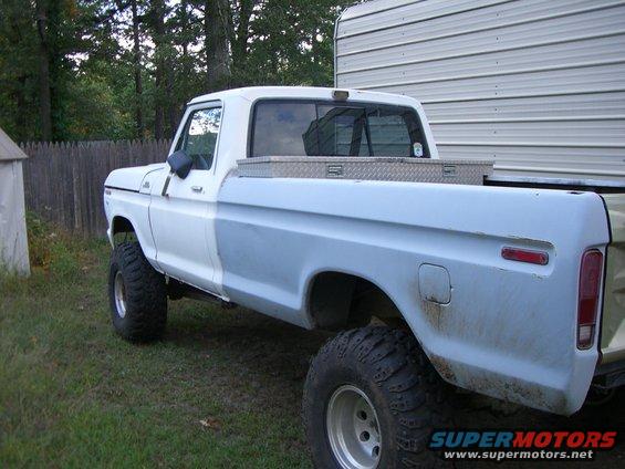 White and gray Ford pickup truck with large tires, seen from the side