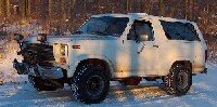 white Ford Bronco with a snow plow attachment in a snowy area