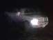 1996 Dodge 1500 - A white pickup truck is parked outdoors at night with its headlights illuminated and driver's door illuminated.