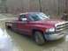 1996 Dodge 1500 - A red 1996 Dodge 1500 pickup truck is partially submerged in muddy water in a wooded area.