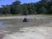 1996 Dodge 1500 - A person rides an ATV through a muddy, off-road area under a clear blue sky.
