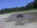 1996 Dodge 1500 - A person rides a modified lawn tractor through a muddy area on a sunny day.