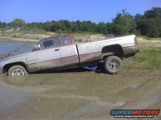 Silver pickup truck stuck in mud, side view. Appears to be a 1994 Dodge Ram 1500