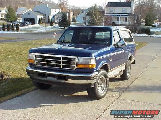 Blue 1996 Ford Bronco parked on a driveway in front of houses