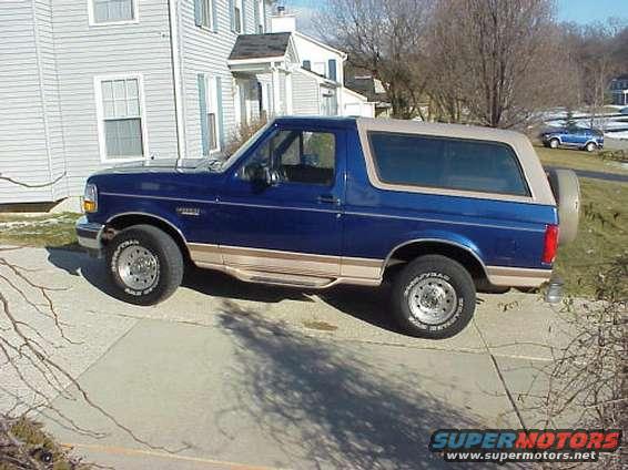 Blue 1996 Ford Bronco parked on a driveway next to a house