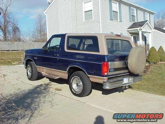Blue and tan Ford Bronco parked on driveway, rear tire carrier visible