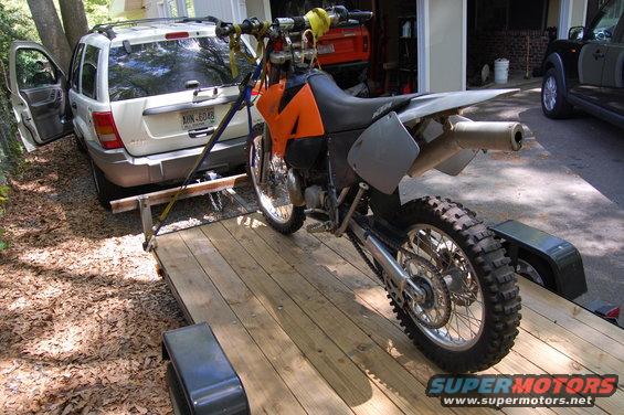 Motorcycle on trailer being towed by white SUV