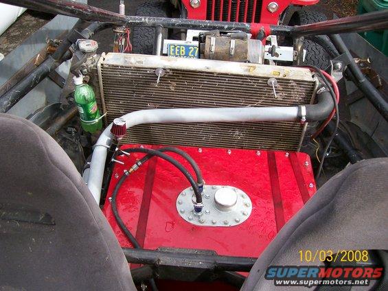 Interior view of a custom off-road vehicle showing a large red fuel tank, radiator, and roll cage