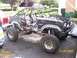 1984 Ford Bronco - A heavily modified vehicle with a roll cage and racing seats is shown in a driveway, with another vehicle partially visible.