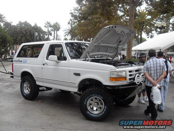 White Ford Bronco, hood open, with aftermarket bumper and lights. Goodyear tires visible