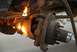 1996 Ford Bronco - A cutting torch is used to heat a rusty suspension part on a vehicle, with sparks flying.