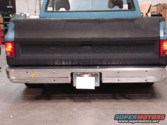 Rear view of a blue and black Chevrolet pickup truck. It has a chrome bumper and a license plate