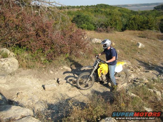 Yellow dirt bike on rocky trail with rider