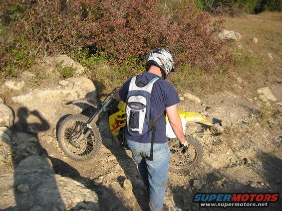 Yellow dirt bike on rocky trail with rider