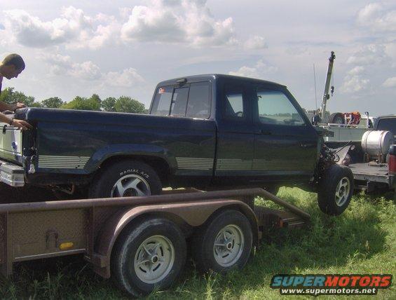 Side view of dark blue pickup truck being loaded onto a trailer