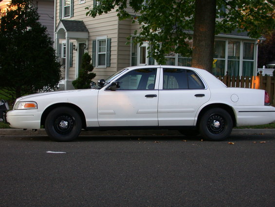 Side view of a white 2000 Ford Crown Victoria sedan parked on a street