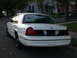 2000 Ford Crown Victoria - White 2000 Ford Crown Victoria sedan parked curbside on a street with houses in the background.