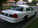 2000 Ford Crown Victoria - This white 2000 Ford Crown Victoria is parked on a residential street with houses in the background.