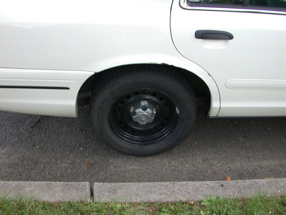 White sedan's rear wheel and door handle, side view