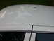 2000 Ford Crown Victoria - The roof of a white car shows signs of rust and reflections of the surrounding environment.