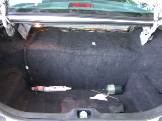 Car trunk with some wires and a tube of sealant