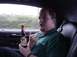 2001 Ford Mustang - A man holds a beer bottle while sitting in the passenger seat of a car, with the landscape blurred in the background.