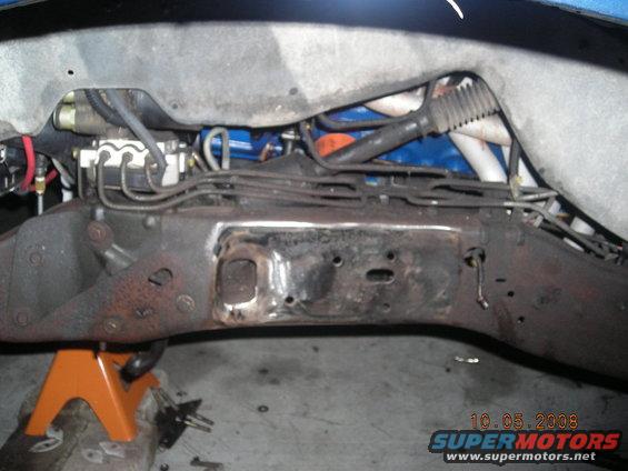 close-up of vehicle frame and brake lines, supported by an orange jack stand