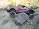 1985 Toyota 4Runner - Pickup truck with significant body damage and aftermarket suspension on a rock obstacle.