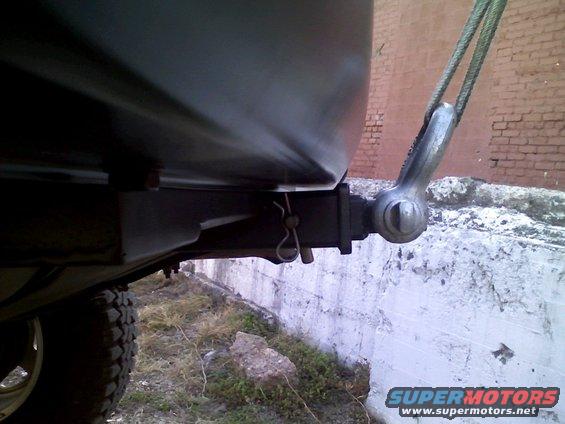 close-up of a trailer hitch receiver with a clevis and pin attached, and a tow cable connected