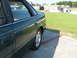 1993 Ford Taurus - The side profile of a sedan shows its rear door, window, and wheel. A building and grassy field are visible behind it.