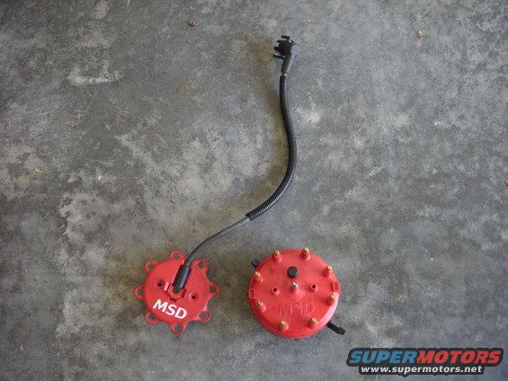 Two red MSD distributor caps and a rotor on a concrete surface