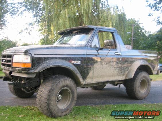 Mud-splattered 1995 Ford Bronco parked on a driveway with trees in the background