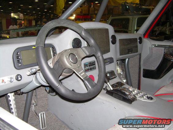 Custom off-road vehicle interior with aftermarket steering wheel, digital display, and shifter