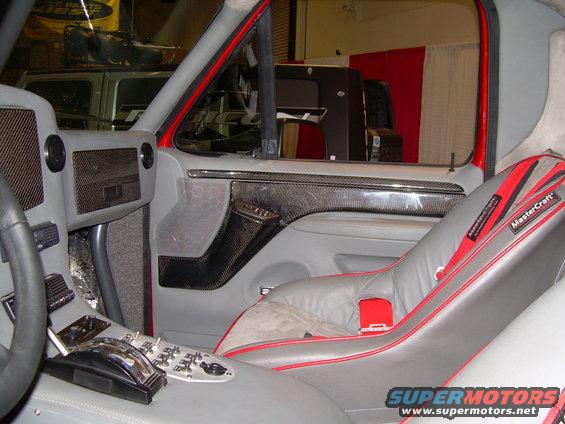 Custom interior with grey seats, red trim, carbon fiber accents, and a modified center console with many switches