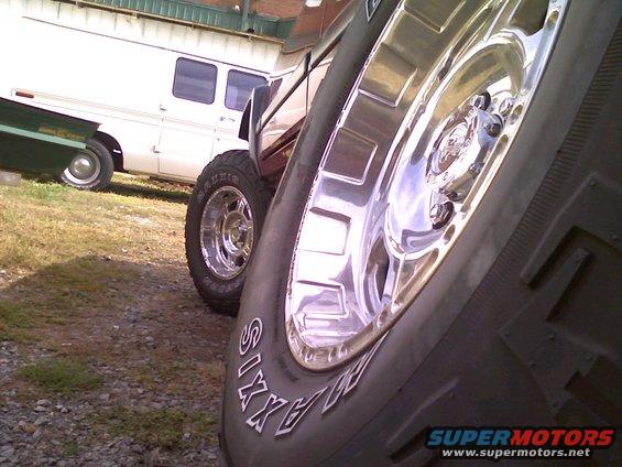 1998 Jeep Cherokee side view, chrome wheels, off-road tires, dark red paint, parked next to a white RV