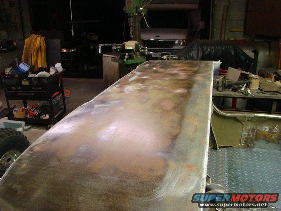 Rusted metal panel with primer and sanding marks, angled view