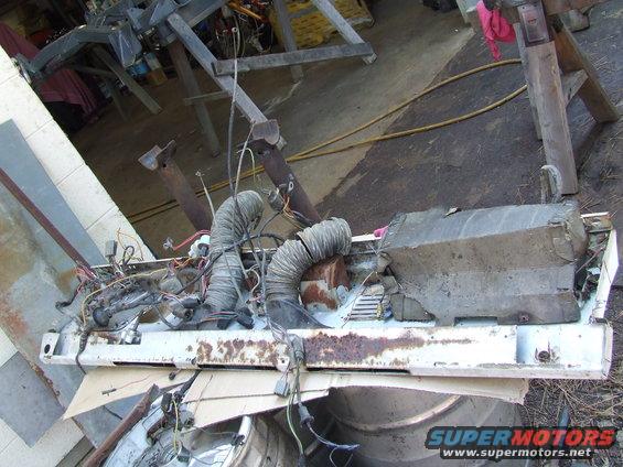 Disassembled vehicle front end with hoses and wires. Supermotors.net logo visible