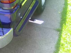 Close-up of a vehicle's rear bumper, exhaust pipe, and tire