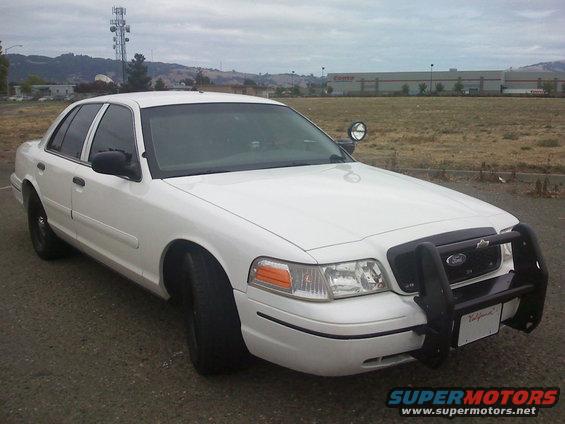 White 2000 Ford Crown Victoria police car with a push bar parked outside