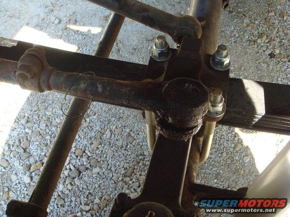 Close-up of rusty tie rod ends, ball joints, and leaf spring U-bolts on a vehicle's suspension