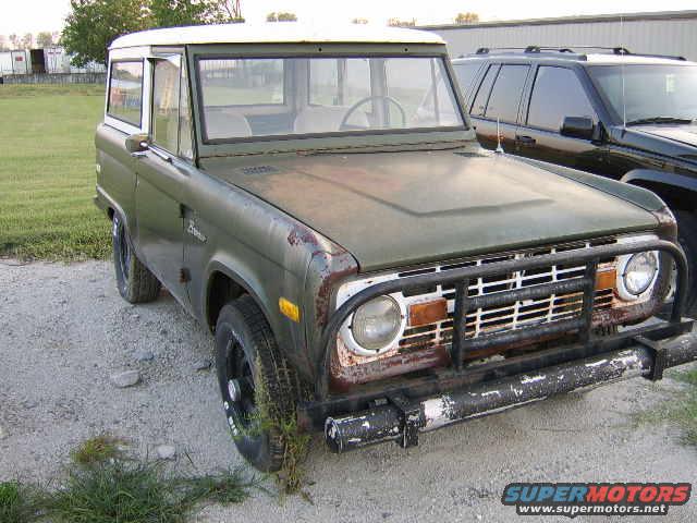Green 1976 Ford Bronco with white roof, rusty front end, and black grille guard
