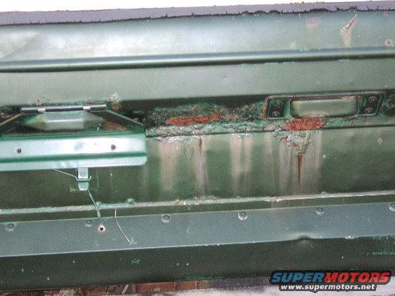 Green door panel with significant rust and damage
